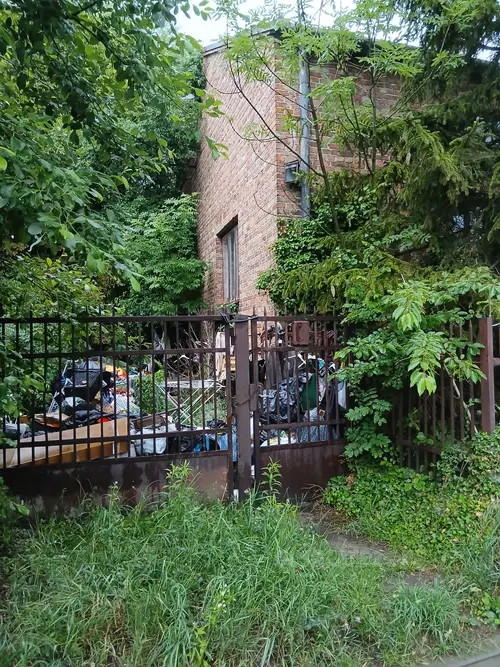 ceglany dom z śmieciami na ogórdku - photo 1/2
